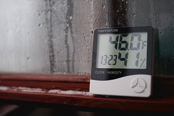 Measurement of air temperature, dew point, humidity with a device (hygrometer), against a background with condensation on the glass, high humidity