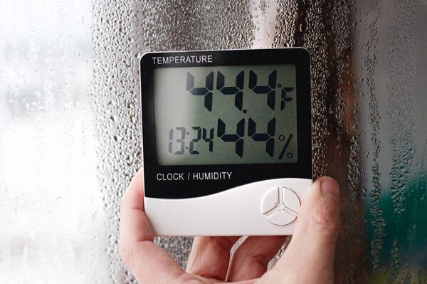 Measurement of air temperature, dew point, humidity with a device (hygrometer), against a background with condensation on the glass, high humidity
