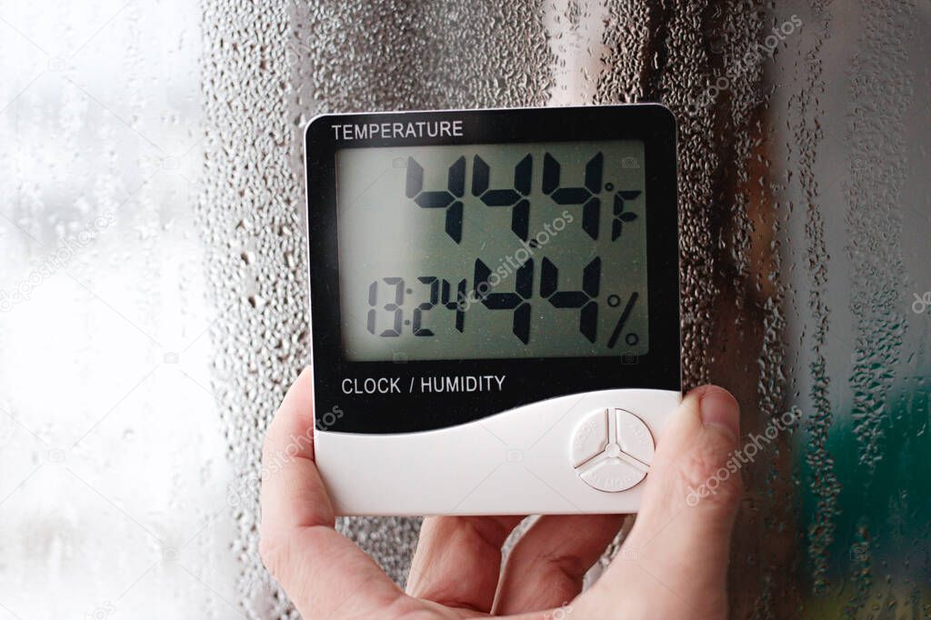 Measurement of air temperature, dew point, humidity with a device (hygrometer), against a background with condensation on the glass, high humidity
