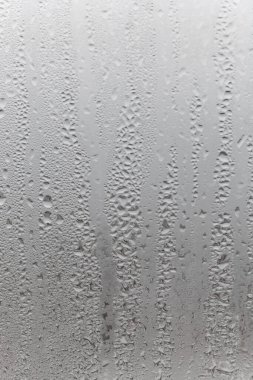 Gri arkaplanda su damlasını kapat, aşağı süzülen su damlacıkları ile sisli cam. Damlayan Yoğunlaşma