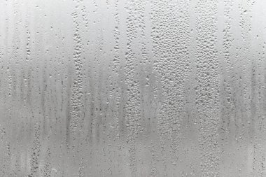 Gri arkaplanda su damlasını kapat, aşağı süzülen su damlacıkları ile sisli cam. Damlayan Yoğunlaşma
