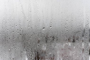 Gri arkaplanda su damlasını kapat, aşağı süzülen su damlacıkları ile sisli cam. Damlayan Yoğunlaşma