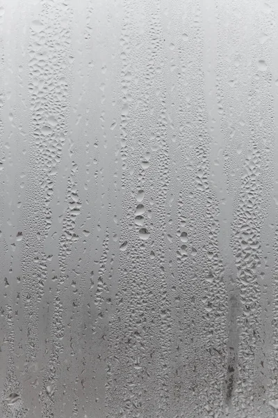 자연적으로 물방울이 유리로 흘러내리고 방에는 습도가 있으며 창문에는 응결되어 중간색 — 스톡 사진