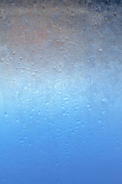 Şeffaf camlarda doğal donmuş yoğuşma damlaları. Kışın donmuş bir pencereden güzel bir arka plan. Cama doku damlatıyor.