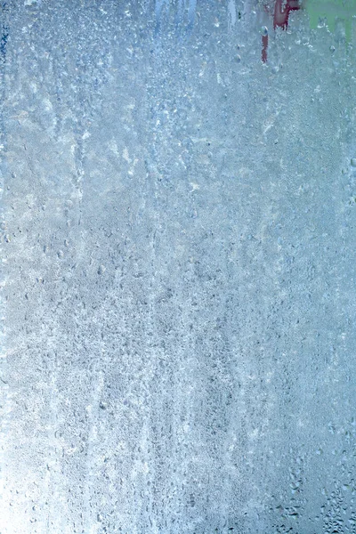 The texture of frozen drops of condensation on a transparent glass window. Water drops. Rain. Abstract texture background. A sharp cold snap, a frozen drop of water on the glass in winter