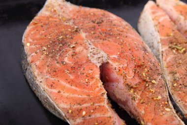 Siyah arka planda baharatlı taze somon bifteği.