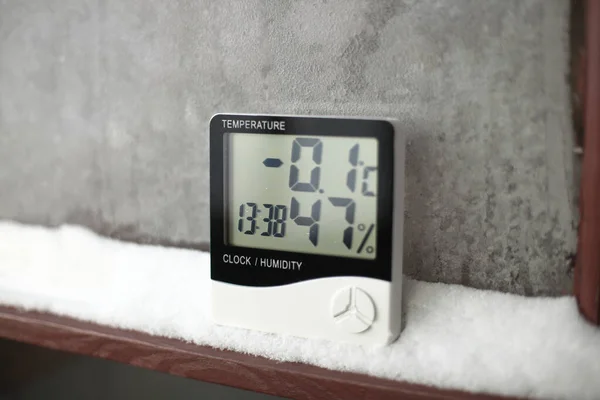 Measurement of the temperature and humidity,  thermometer and hygrometer on a window with snow on the background of frozen glass