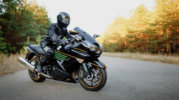 Sports bike rider wearing a helmet and leather protective gear on a fast sports bike