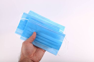 Beyaz arka planda mavi cerrahi maske tutan ilk kişi. Virüsün yayılmasına karşı koruyucu solunum maskesi. Kapat, boşluğu kopyala, üst görünüm, düz yatış