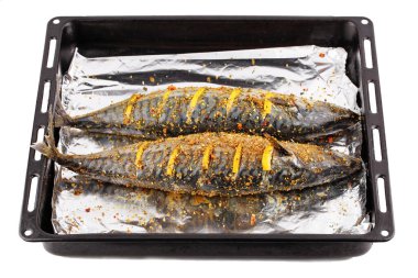 Baharatlı folyo ve limon dilimleri ile pişirmeye hazır iki çiğ deniz balığı.