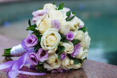 Bulanık arka planda, doğal çiçeklerden oluşan güzel bir düğün buketi granitin üzerinde yatıyor.