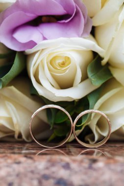 Granit tezgahtaki alyanslar güzel bir çiçek buketinin arka planında.