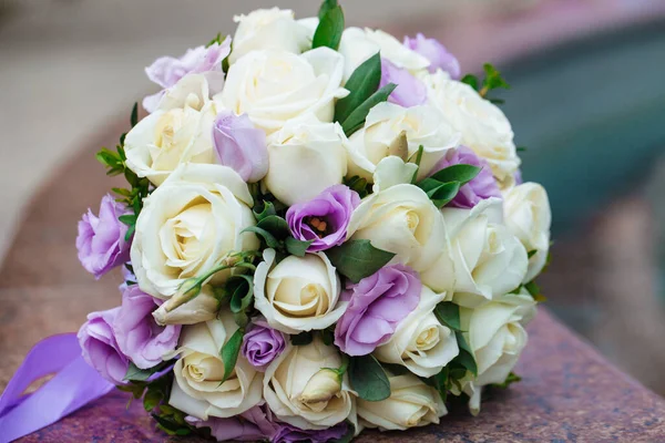 Beautiful wedding bouquet of natural flowers on a blurred background lies on granite