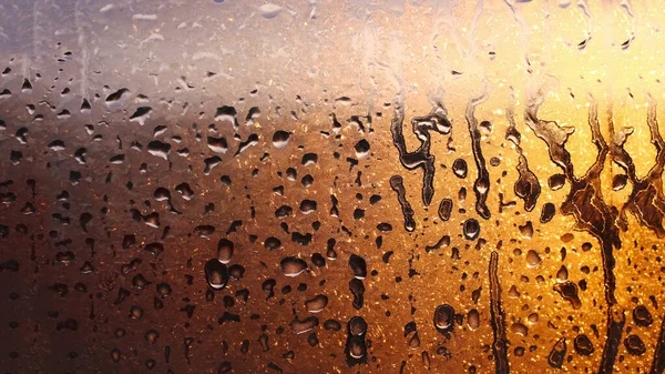 Drops of condensate on the sweaty glass window. Cold foggy glass. Wet window background, texture condensation with dripping drops