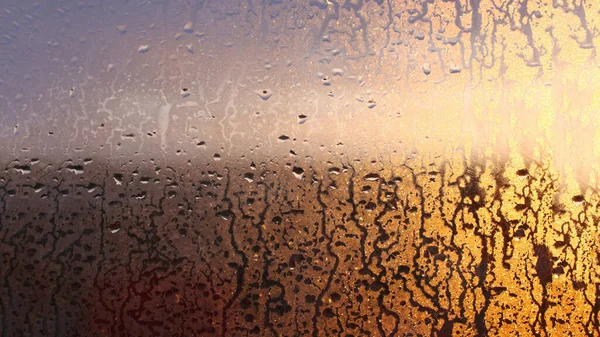 Drops of condensate on the sweaty glass window. Cold foggy glass. Wet window background, texture condensation with dripping drops