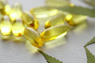 Kenevir CBD kapsülleri, yaprakları, CBD kenevir yağı kapsülleri içeren, kopyalama alanı olan beyaz bir tıbbi kenevir ürünüdür.