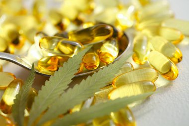 Kenevir CBD kapsülleri, yaprakları, CBD kenevir yağı kapsülleri içeren, kopyalama alanı olan beyaz bir tıbbi kenevir ürünüdür.