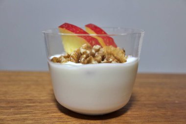Dilimlenmiş elma ve çiğ cevizle kaplı yoğurt.
