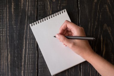 Eli kalem bir defterde yazıyor.