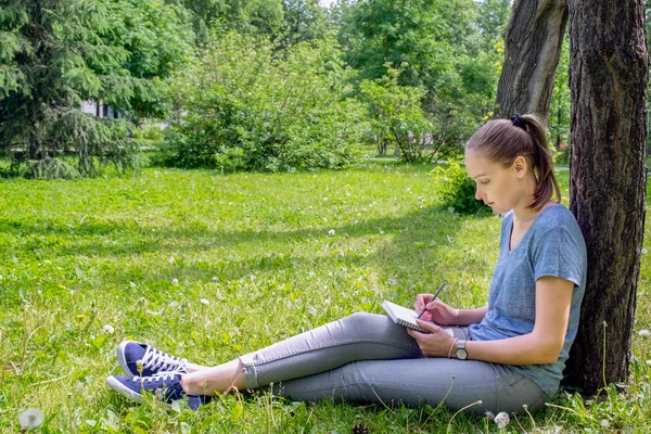 Kvinnan drar sitter på gräset — Stockfoto