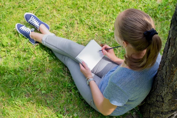 Woman draws sitting on grass