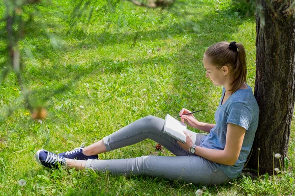 Vrouw trekt zittend op het gras — Stockfoto