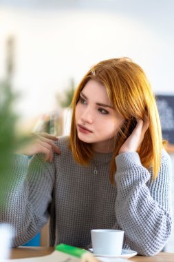 Bir fincan kahve ile bir masada oturan kız