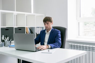 Ofiste dizüstü bilgisayarlı bir adam var.