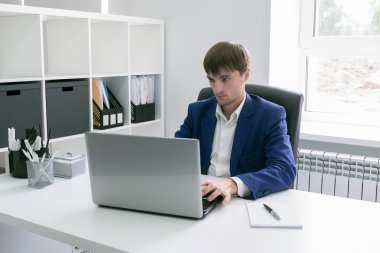 Ofiste dizüstü bilgisayarlı bir adam var.