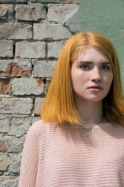 Tuğla duvarın yanında kırmızı saçlı kız