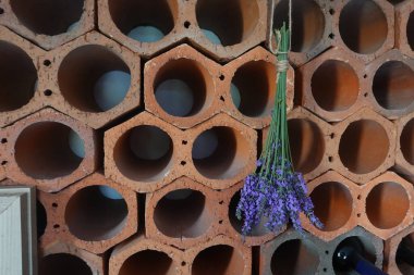 İple bağlanmış lavanta çiçekleri kırsal bir altıgen şarap rafında asılı duruyor ve bir kır evi atmosferi yaratıyor.