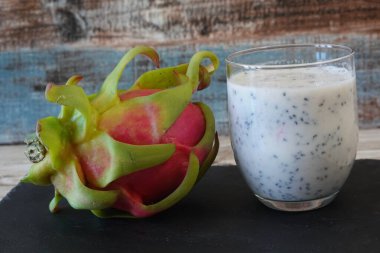 Taze meyve dilimlenmiş bardakta ejderha meyveli pitaya smoothie, sağlıklı ve ferahlatıcı yaşam tarzı için canlı pembe tropikal süper yiyecek.