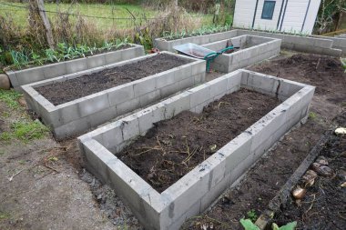 Zengin topraklarla dolu çoklu beton bloklu yataklar arka bahçedeki organik sebze bahçesine hazırlanıyor.