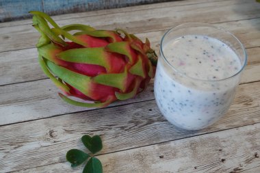 Kırsal bir masada taze tropikal pitaya meyvesi ile bardakta ejderha meyveli pitaya smoothie.