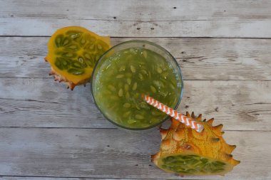 Boynuzlu kavun kiwano suyu bardakta, pipetle ve kiwano meyvesiyle ferahlatıcı bir yaz içeceği hazırlıyorum.