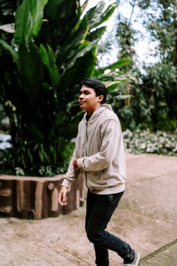 Rahat bir Asyalı genç adam, yemyeşil yeşilliklerin ve doğal çevrenin ortasındaki temiz havanın tadını çıkarıyor..