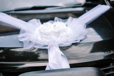 Koyu renk bir düğün arabası zarif beyaz kurdelelerle süslenir ve özel bir kutlamaya hazırdır..
