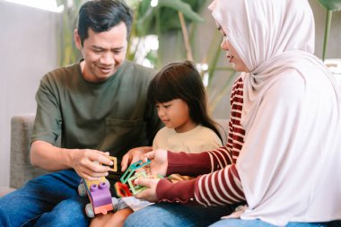 Asyalı bir aile, evde renkli manyetik yapı oyuncaklarıyla oynayarak birlikte kaliteli zaman geçirmekten zevk alır. Ebeveynler ve çocuklar eğlenceli ve eğitici bir aktivite içinde, yaratıcılığı ve öğrenmeyi teşvik ediyorlar..