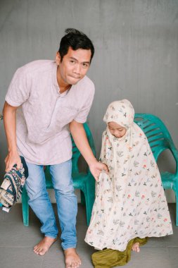 Bir baba ve küçük kızı evlerinde dini bir dua ayini için hazırlanırken samimi bir anda yakalanırlar. Çocuk çiçek desenli bir dua elbisesi giyiyor..