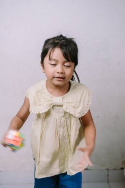 Sevimli genç bir kız renkli bir bulmaca küpünü çözmeye odaklanmış. Bu resim, öğrenme ve geliştirme temaları için ideal olan çocukluk konsantrasyonu ve oyuncu problem çözme yöntemlerini yakalar..