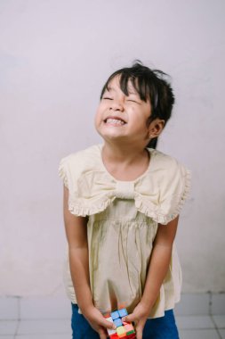 Enfes bir genç kız, elinde canlı, renkli bir bulmaca küpü, problem çözmeyi ve çocukluk oyununu sembolize ederken yoğun bir neşe ve konsantrasyon gösteriyor..