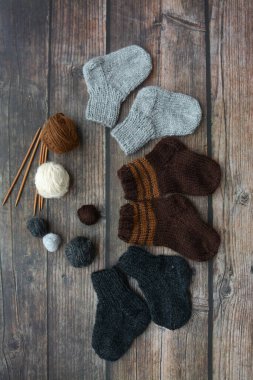 Koyu ahşap arka planda yün iplikten yapılmış küçük ve sıcak yeni doğan çoraplar.