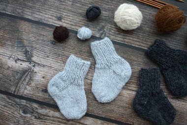 Koyu ahşap arka planda yün iplikten yapılmış küçük ve sıcak yeni doğan çoraplar.