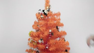 Beyaz arka planda süslemeleri olan yapay turuncu Noel ağacı. Tahta minyatür dekorasyonlar mevsimlik minyatürün renkli dallarında asılı..