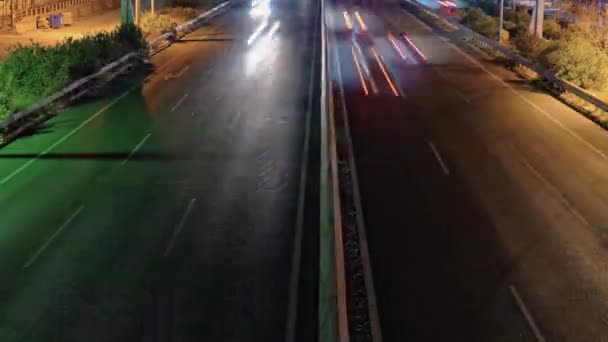 中央で区切られた高速道路での高架交通時間の経過 ギリシャのテッサロニキの反対方向にライトトレイルを残して通過車とヨーロッパのマルチレーン道路の夜のトップパノラマ — ストック動画