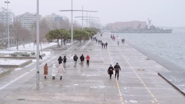 ギリシャのテッサロニキメディアの正面は 群衆が移動して 大雪の都市の中心に当たります 暖かい服を着た人々とコヴィト 19マスクは雪の降る悪天候の下を歩く — ストック動画