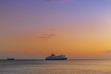 Yunanistan 'ın Selanik kentindeki şehir limanına giden yolcu gemisi. Sakin deniz limanına girmek için bekleyen ticari teknenin akşam manzarası.
