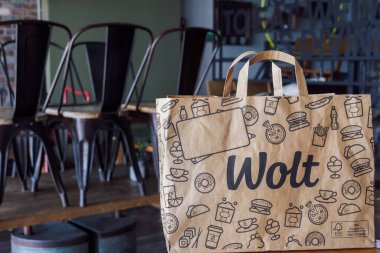Wolt food delivery bag with company logo, on restaurant. Finish company paper bag with handle, used by platform courier partners in Thessaloniki, Greece. clipart