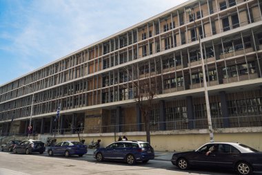 Selanik, Yunanistan Adliye Binası cephesinde Yunan bayrağı sallanıyor. Dışarıya park etmiş taksiler ve levhalı adalet binasının alçak açılı görüntüsü..