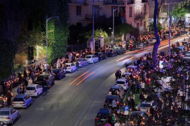 Selanik, Yunanistan - 01 Mayıs 2021: Ortodoks Paskalya 2021 Anastasi Dirilişi. İlahi Edebiyat Servisi 'ne katılmak için kilisenin önünde toplanan sadık maskeler ve yanan mumlar..